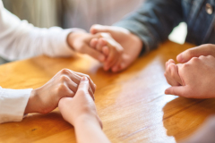 Group of people sitting in a circle holding hands and pray together or in therapy session